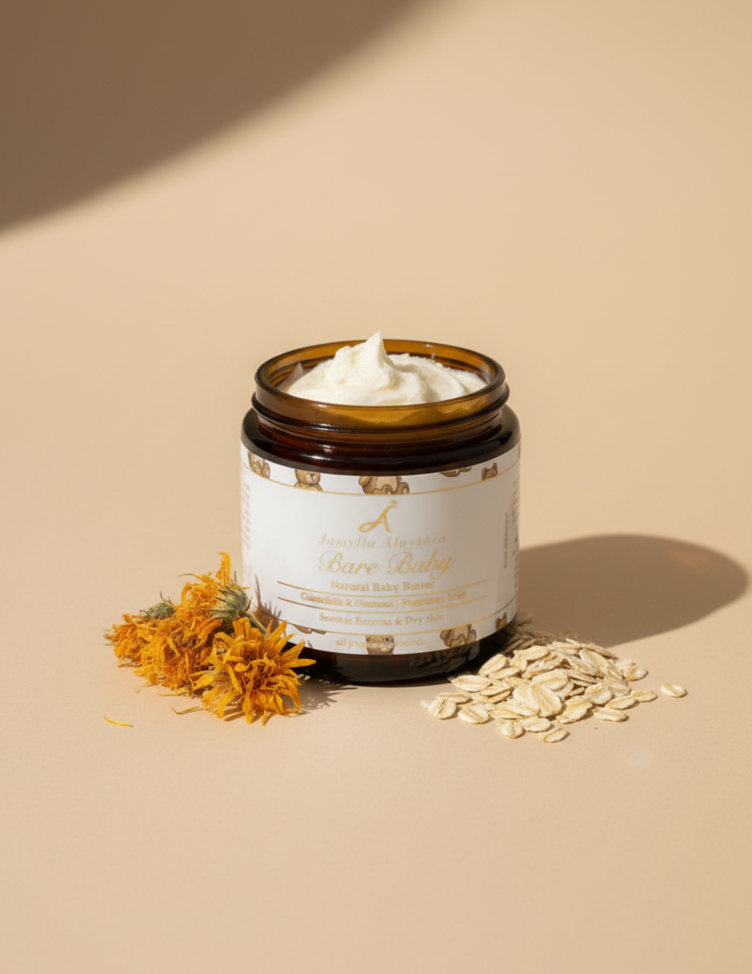 Jar of Baby bare body butter with the liid off showing creamy whipped body butter, with calendula flowers and oats on the surface near the jar on a beige background