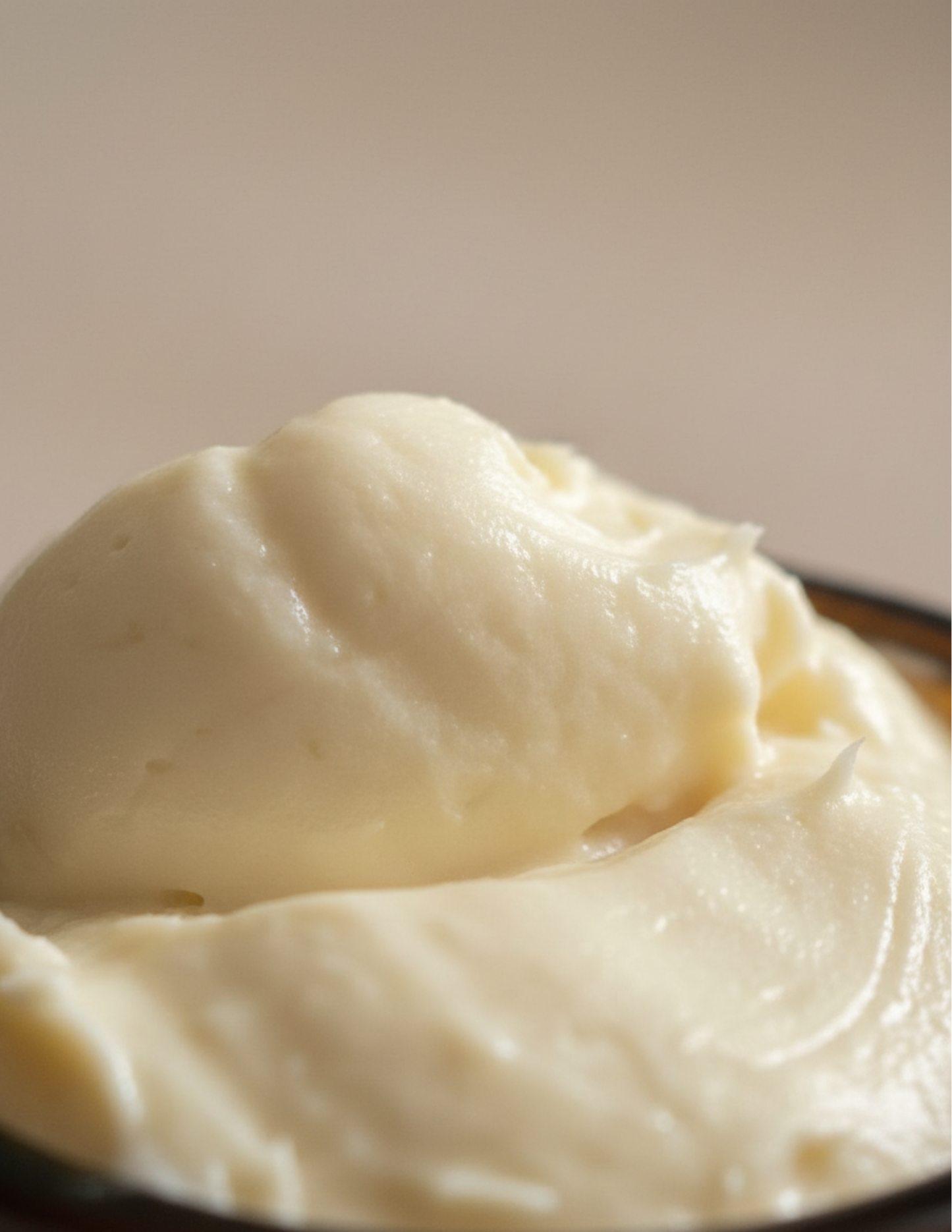 Close-up of whipped creamy body butter that looks like a scoop of vanilla ice cream on a plain background