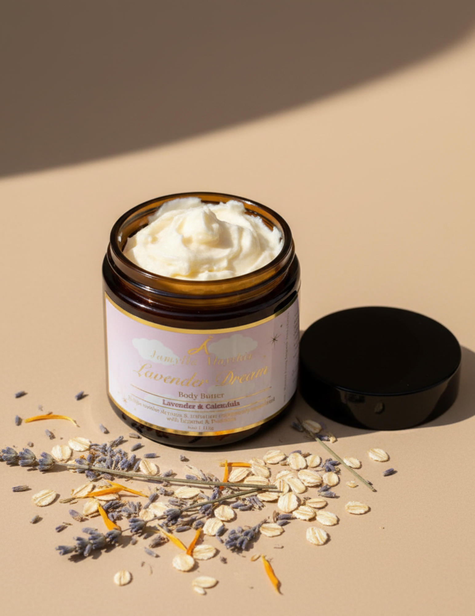 Amber glass Jar of lavender dream, with the lid off showing the whipped body butter, with lavender oats and calendula leaves on a beige background