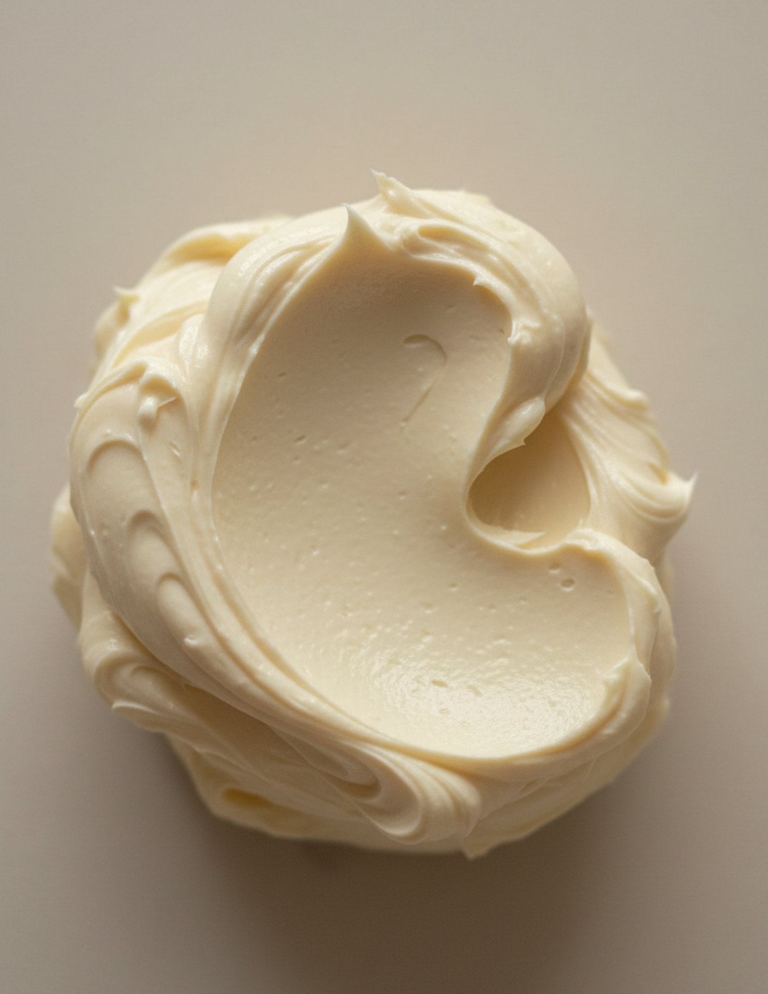 Close-up of a swirl of Lavender Dreams creamy beige whipped body butter on a light background