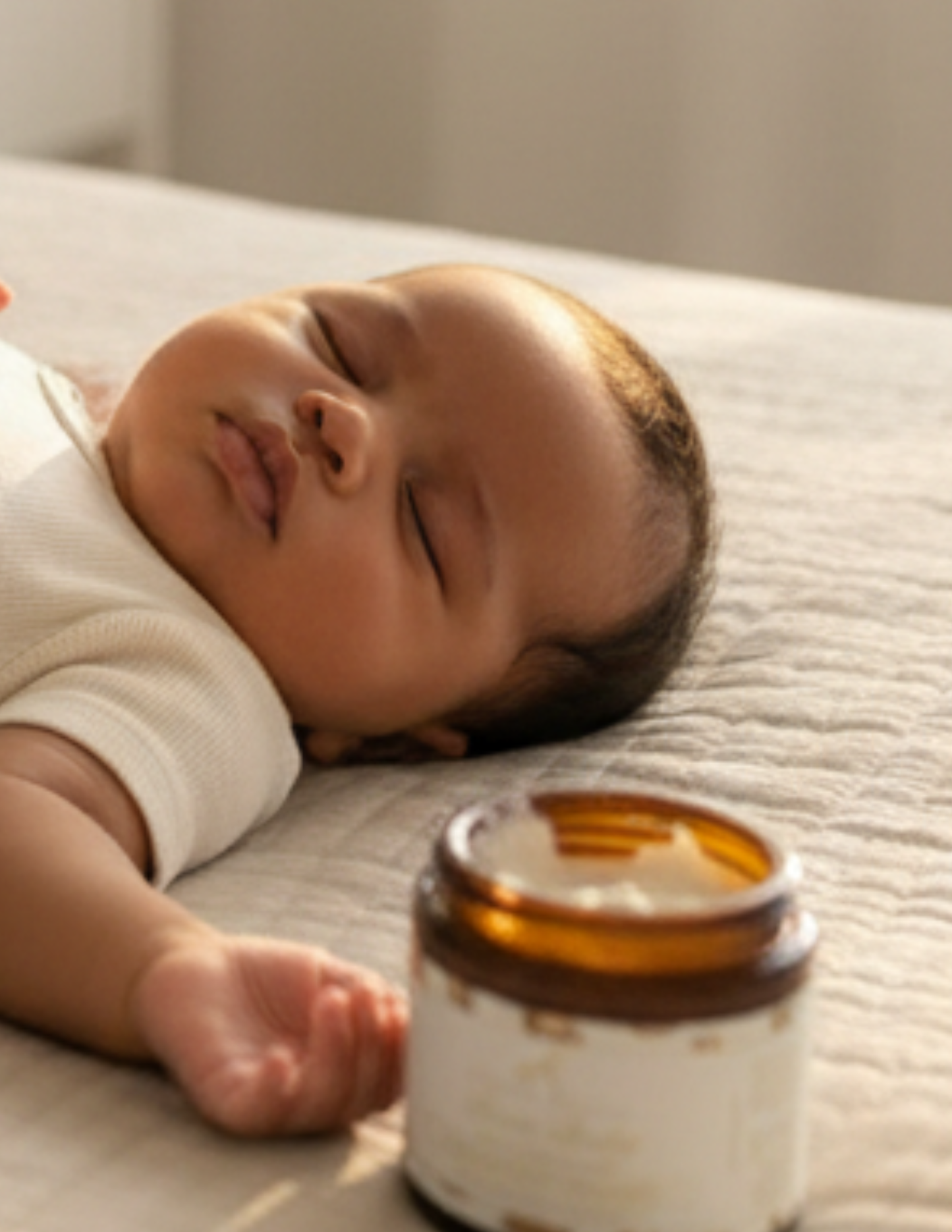 Baby lying on a textured surface next to a jar of open Baby bare whipped baby butter
