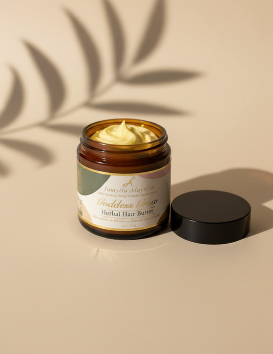 Jar of open herbal hair butter showing the yellow butter, with a black lid to the side, on a beige background